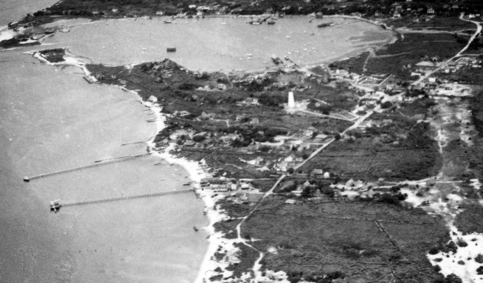 1936 oblique aerial photograph of Ocracoke village, North Carolina, showing the lighthouse, the shallow Silver Lake harbor and two long piers into Pamlico Sound