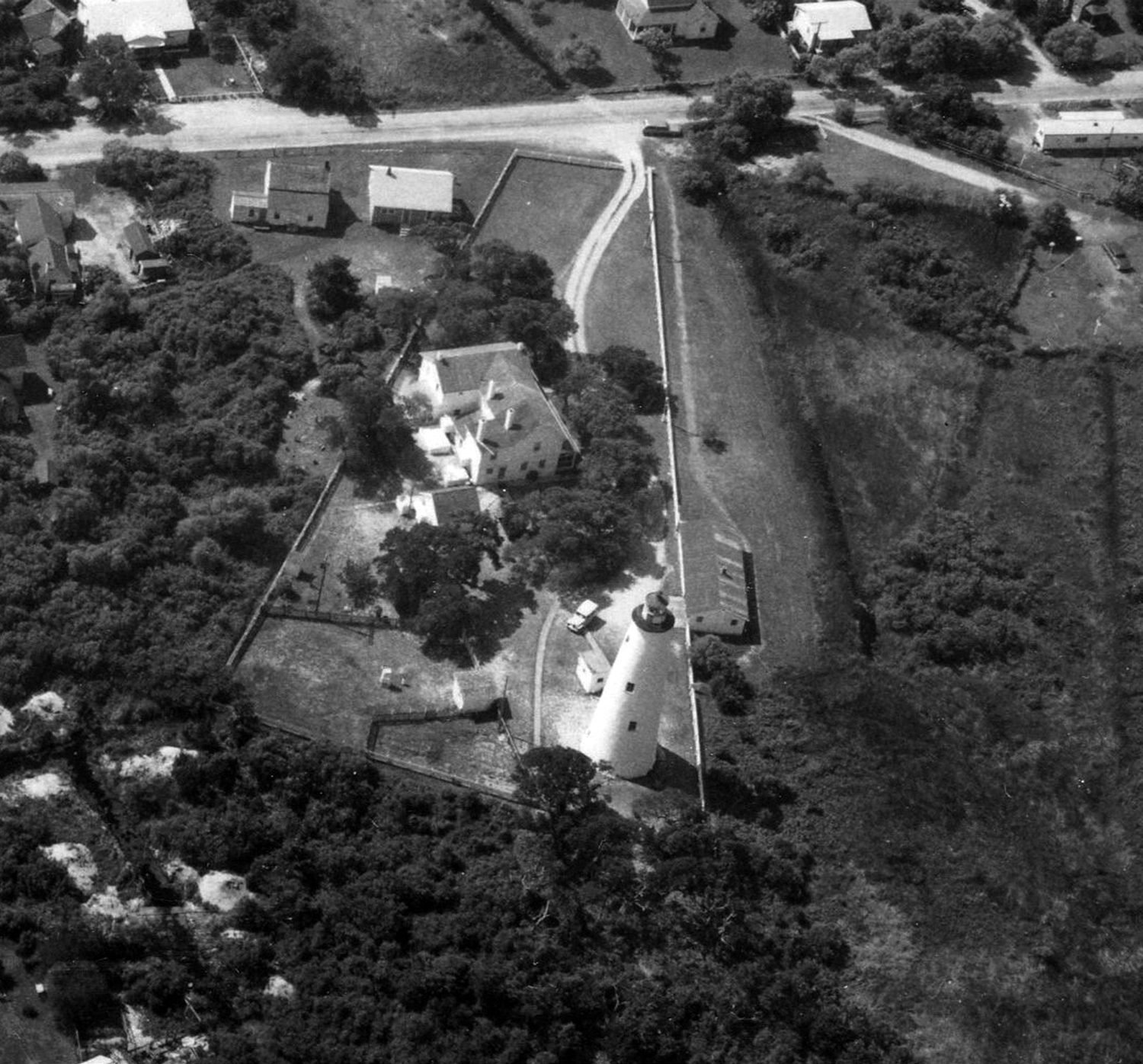 1966 aerial photograph looking down on Ocracoke Light Station, showing the lighthouse tower, double keepers' quarters, garage and chicken house