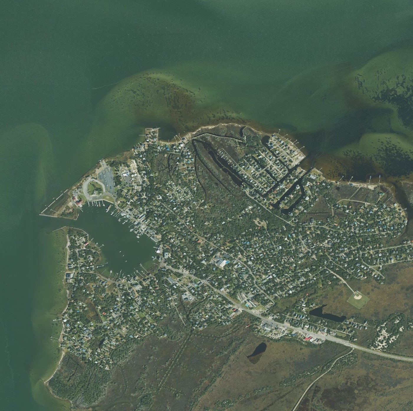 Recent color aerial orthophoto of Ocracoke village showing Silver Lake harbor, ferry terminal, NC 12 and Springer's Point, framed identically to the 1993 image