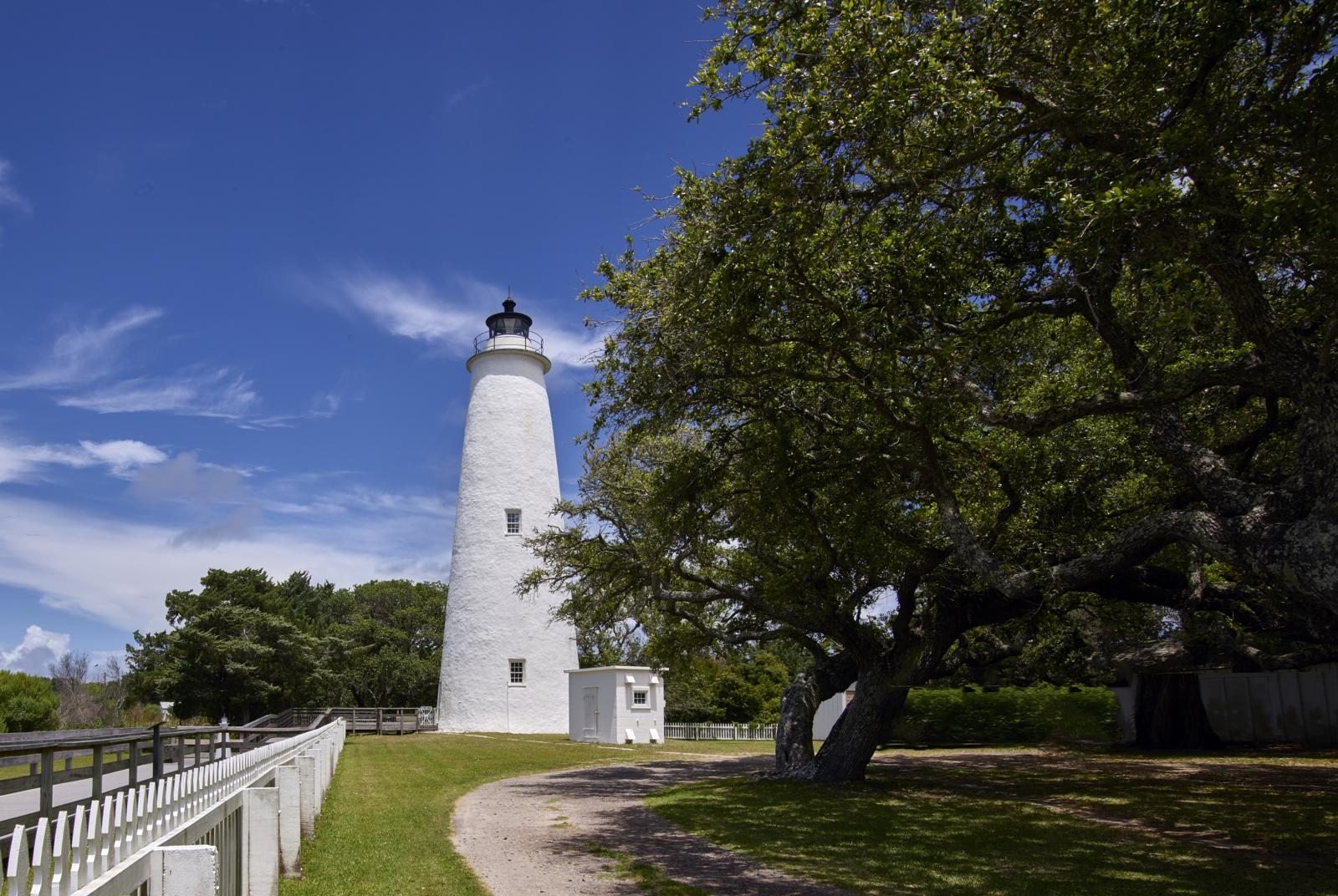 The white conical tower of the Ocracoke Lighthouse rising above trees on Ocracoke Island, North Carolina